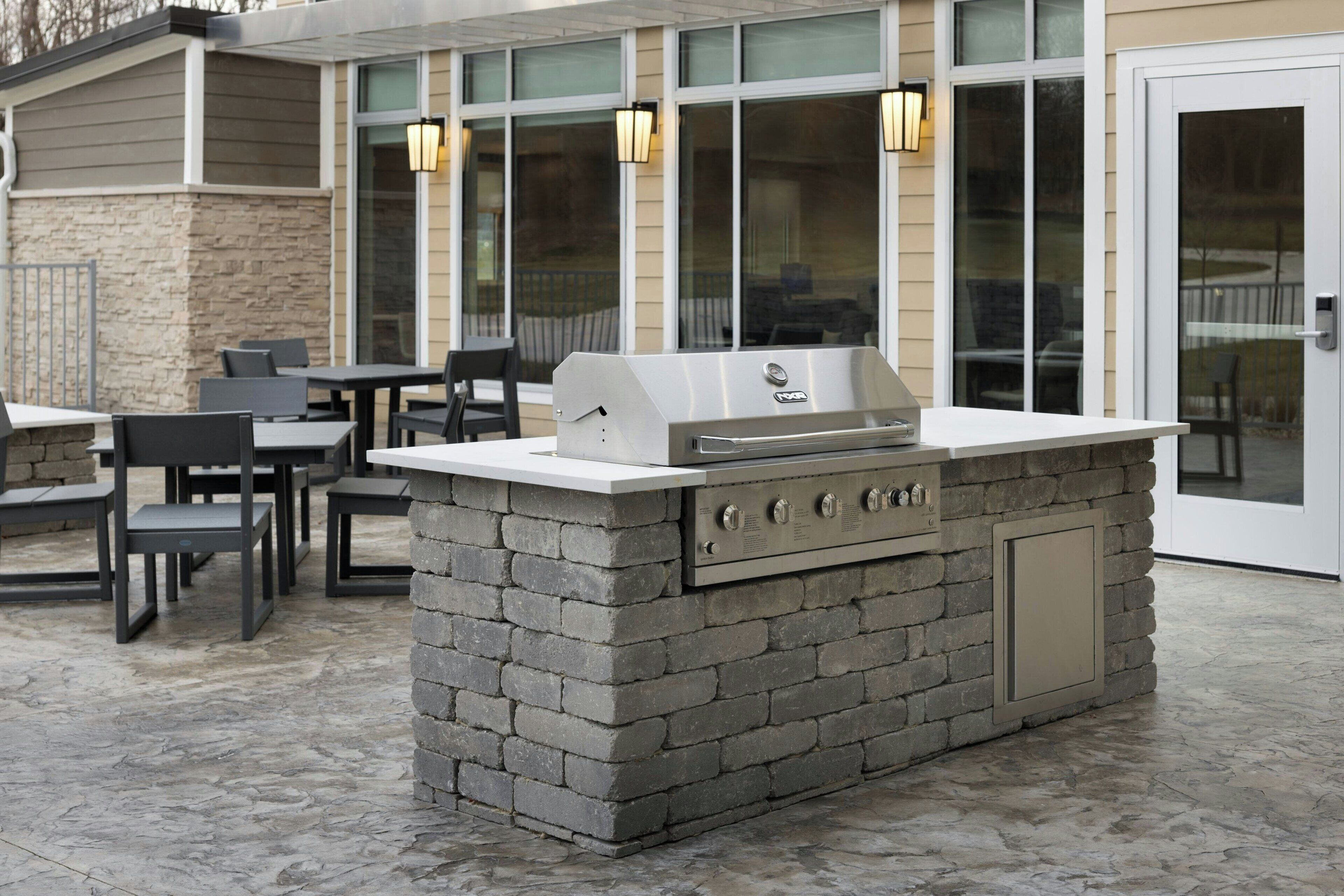 An outdoor patio with a stone barbecue station, tables, and chairs.