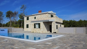 A two-story stone house with a swimming pool.