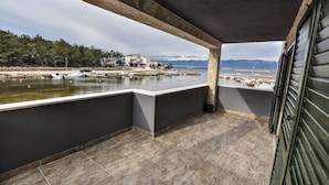 A balcony with a view of a calm body of water, boats, and distant mountains.