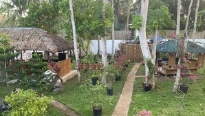 Un jardin agrémenté de plantes en pot, une construction à toit de chaume et une clôture en bois.