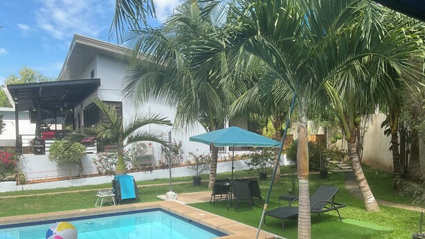 Un jardin avec une piscine, des palmiers et du mobilier d’extérieur.