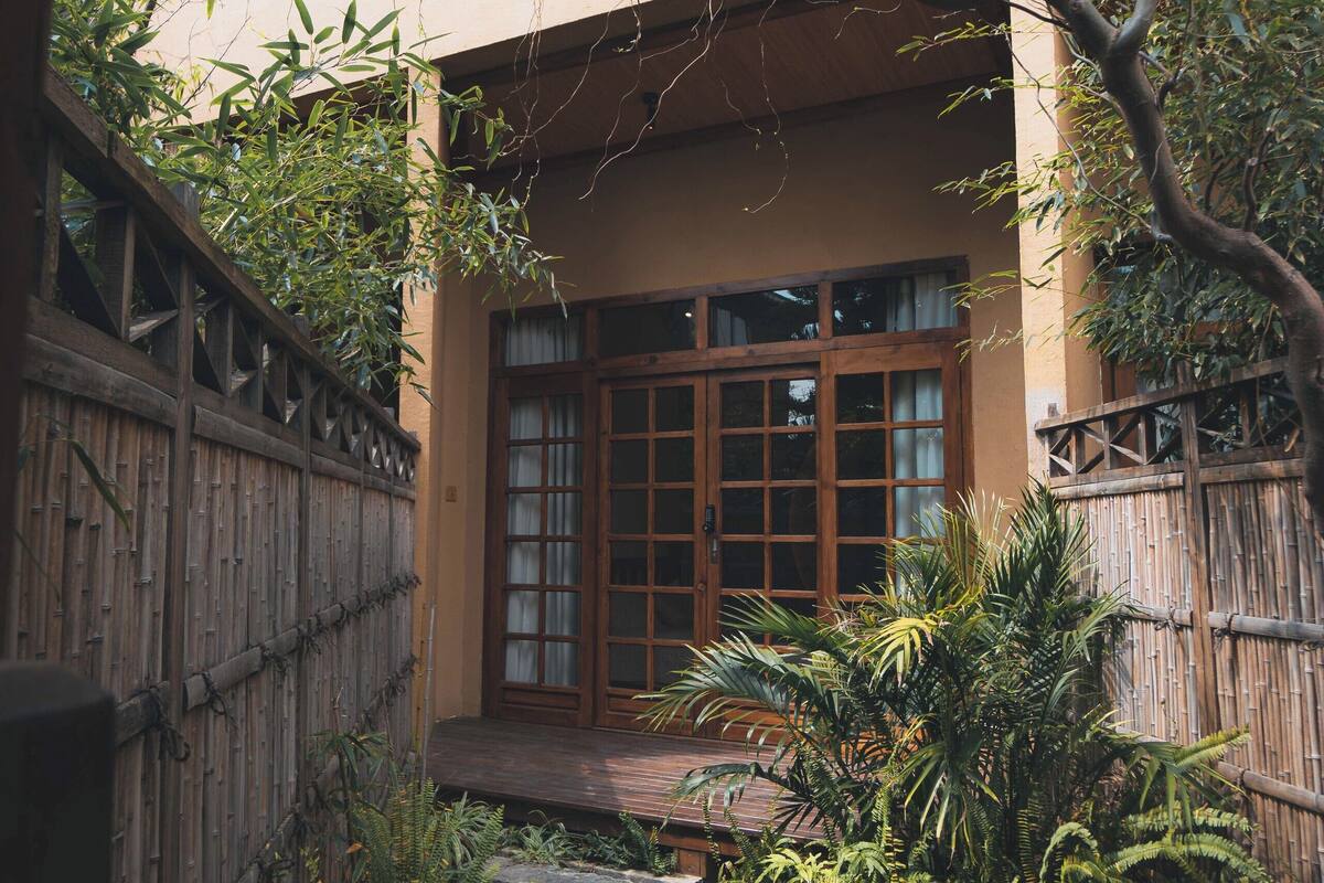 A traditional building with a wooden gate, a stone pathway, and lush greenery.