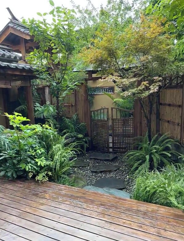 A wooden deck with a garden area featuring various plants and a bamboo fence.