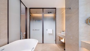 Een moderne badkamer met een vrijstaand bad, een douchecabine met glazen wanden en een wastafel met spiegel.