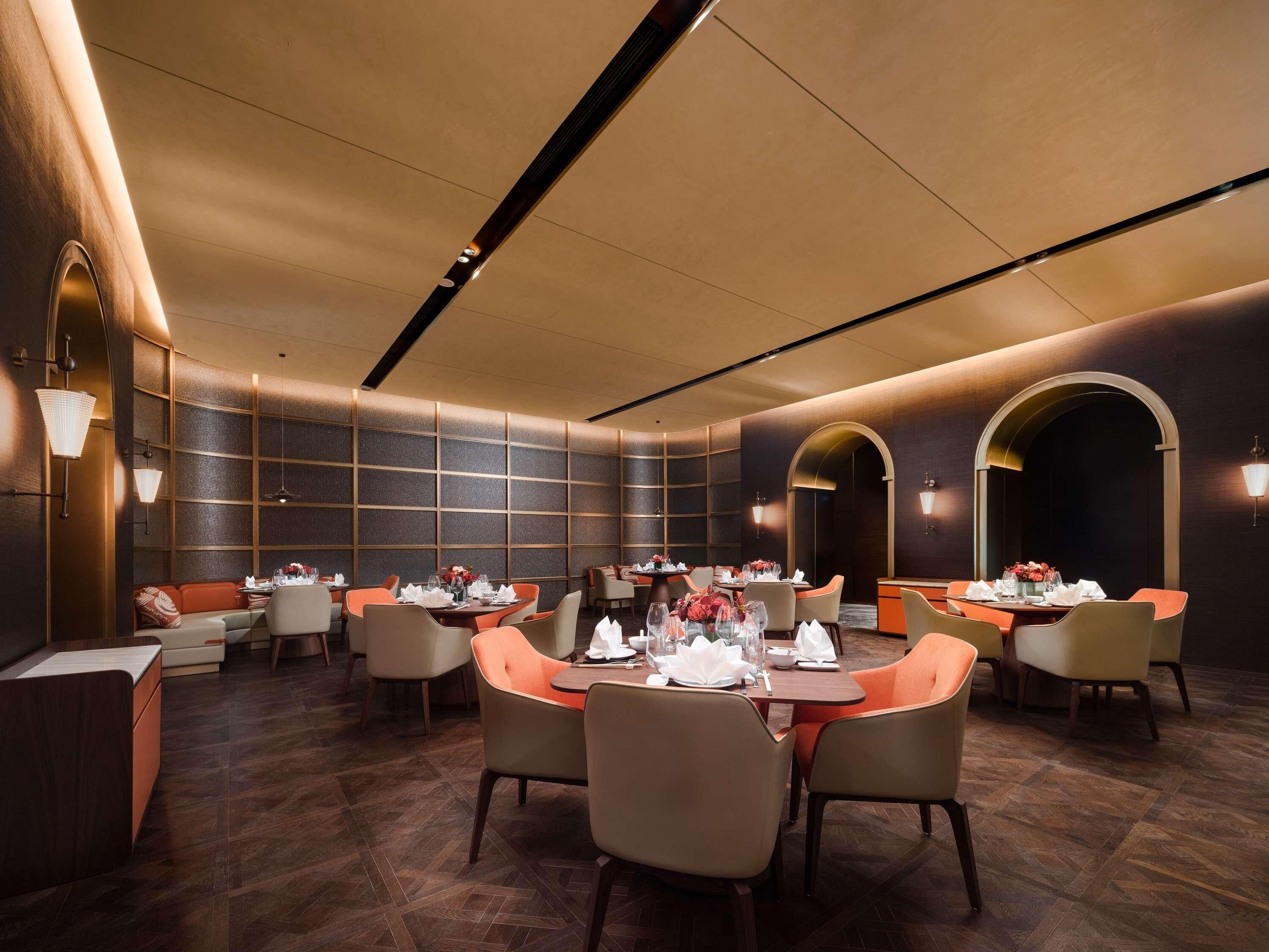 A modern dining area with multiple tables, chairs, and ambient lighting.