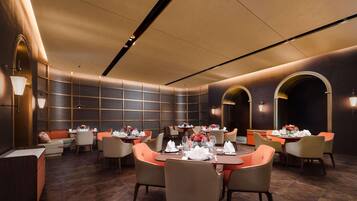 A modern dining area with multiple tables, chairs, and ambient lighting.