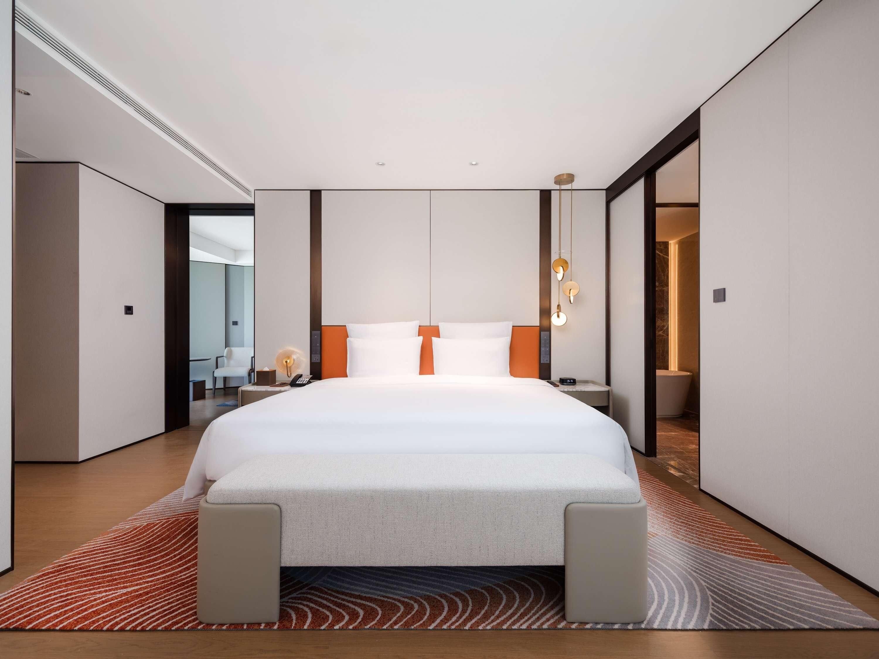 A modern hotel room with a large bed, a desk, and a chair.