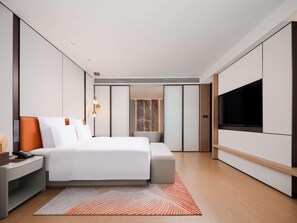 A modern hotel room with a large bed, bedside table, and a flat-screen TV mounted on the wall. - Pullman Chongqing Xiyue (Chongqing)