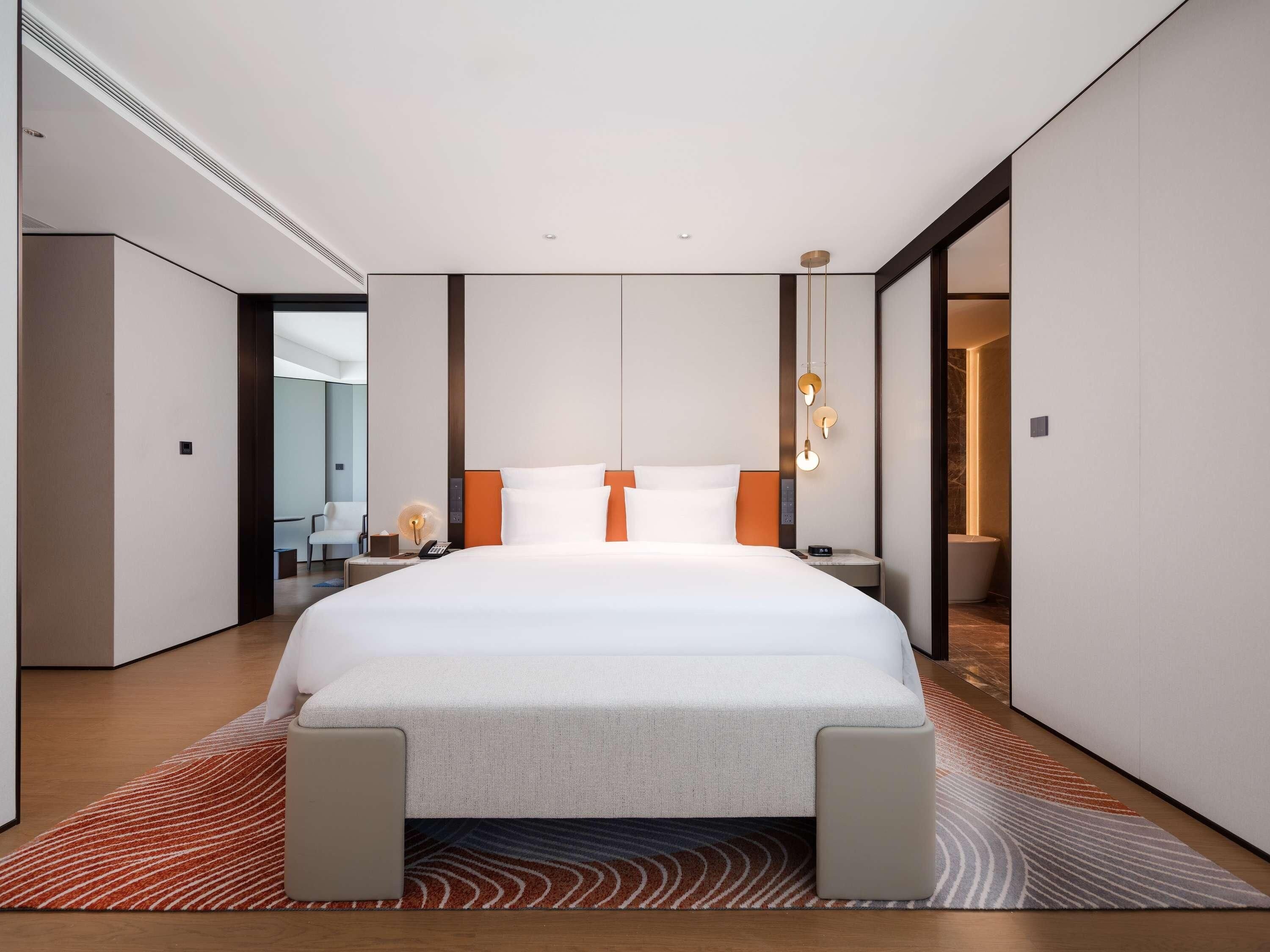 A modern hotel room with a large bed, a desk, and a chair.