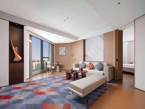 A modern living room with a sofa, coffee table, and a large window offering a city view. - Pullman Chongqing Xiyue (Chongqing)