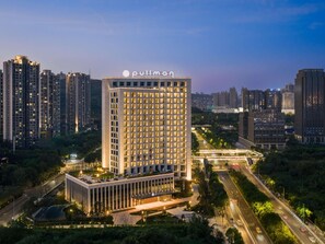 A high-rise building with a prominent 'pullman' sign, surrounded by other tall buildings and a well-lit urban environment. - Pullman Chongqing Xiyue (Chongqing)