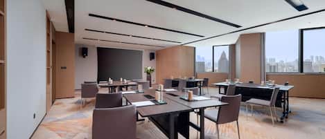 A modern conference room with multiple tables, chairs, and a large window offering a city view.
