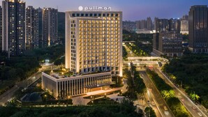 Un edificio de gran altura con un llamativo letrero "Pullman", rodeado de otros edificios altos y un entorno urbano bien iluminado.
