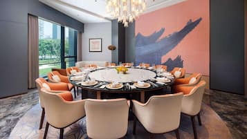 Uma sala de conferências com uma mesa redonda, cadeiras e um candelabro.
