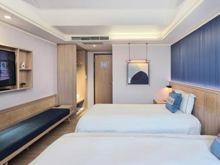 A hotel room with two beds, a TV, a desk, and a wall-mounted artwork.
