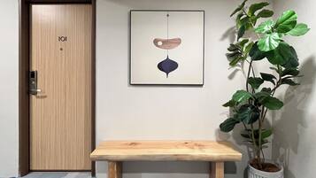 A wooden door with a lock, a bench, a framed artwork, and a potted plant.