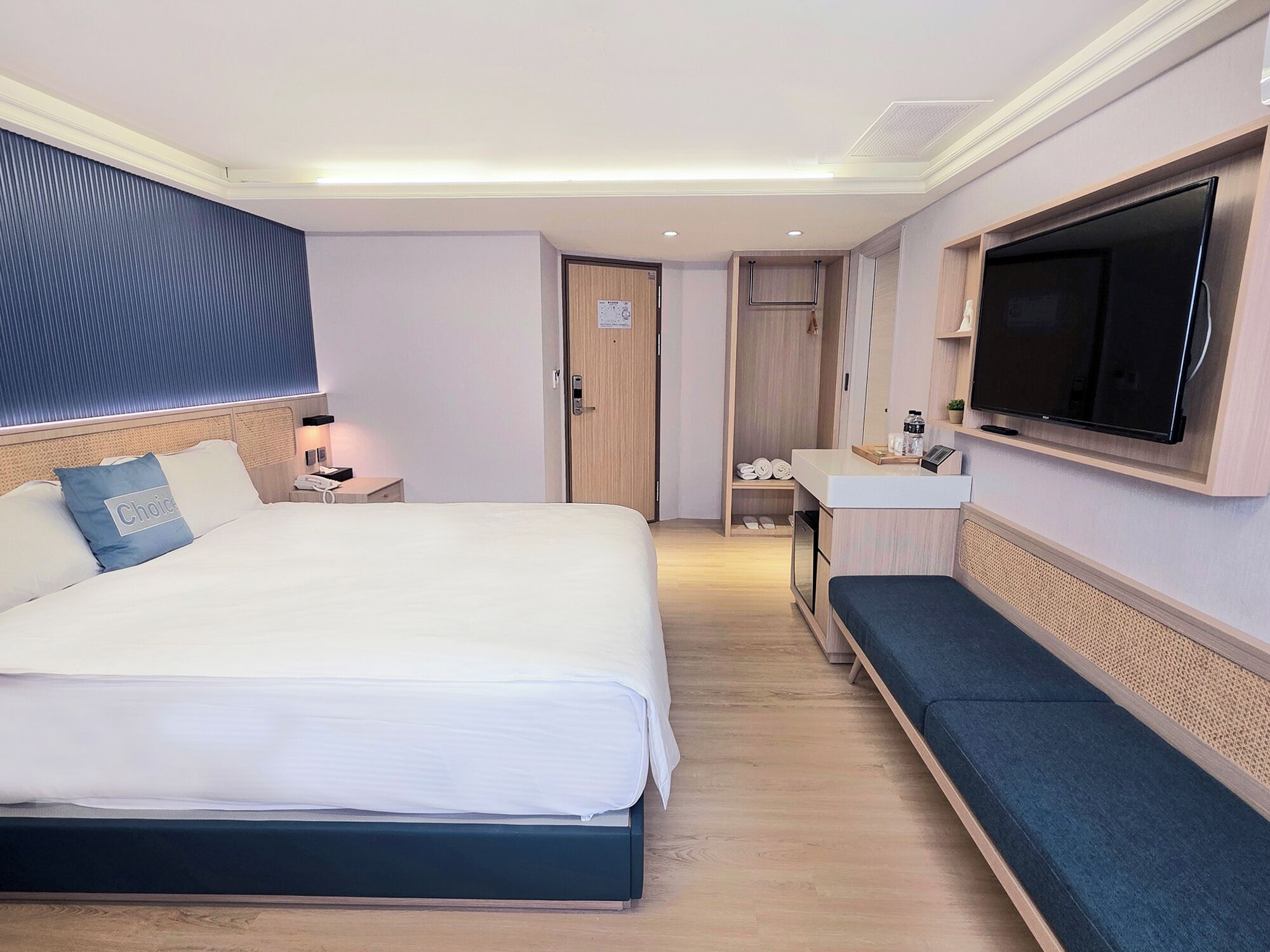 A hotel room with a large bed, a TV mounted on the wall, a desk, and a wardrobe.