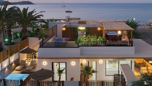 Een moderne villa met een zwembad op het dak, buiten zitplaatsen en uitzicht op zee.