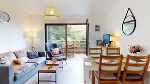 Un salon comprenant un canapé, des fauteuils, une table à manger et un balcon avec vue.