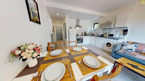 Un espacio habitable compacto con comedor, kitchenette y sofá.