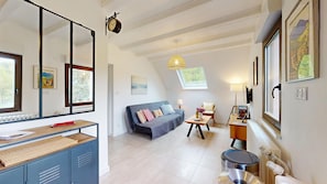 Ein modernes Wohnzimmer mit einer Couch, einem Esstisch und einer Küchenzeile mit Herd.