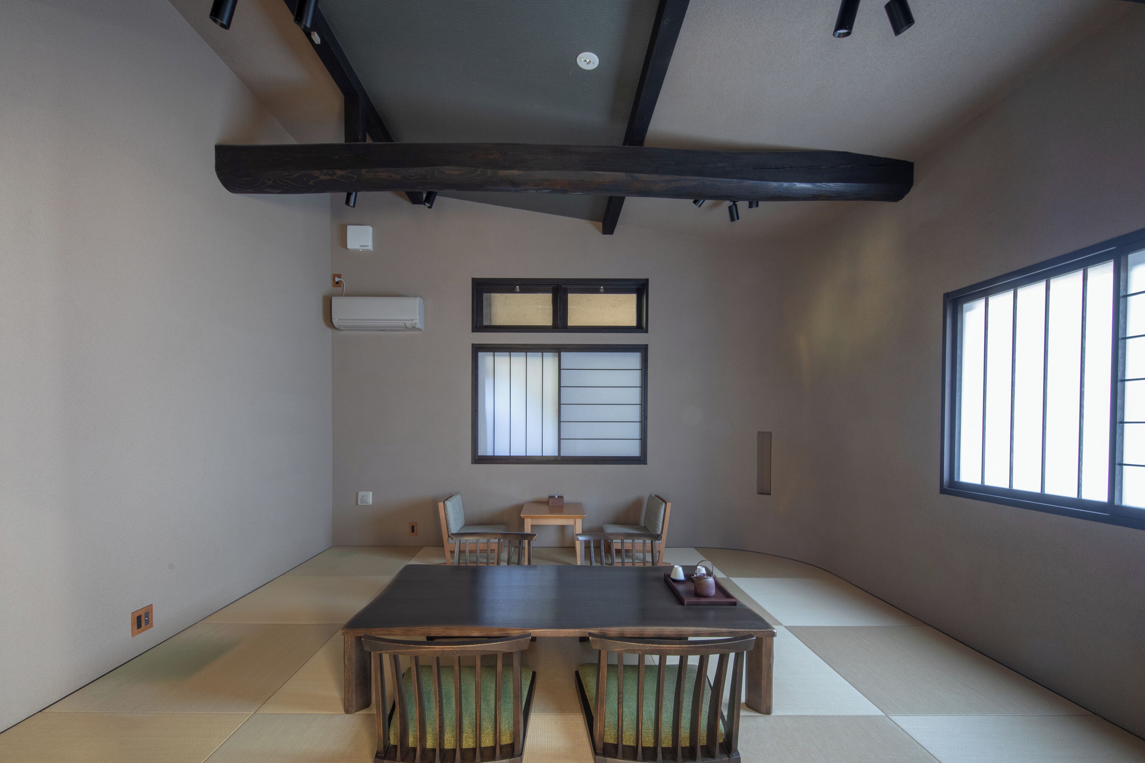 A traditional Japanese-style room with tatami flooring, a low table, and wooden chairs.