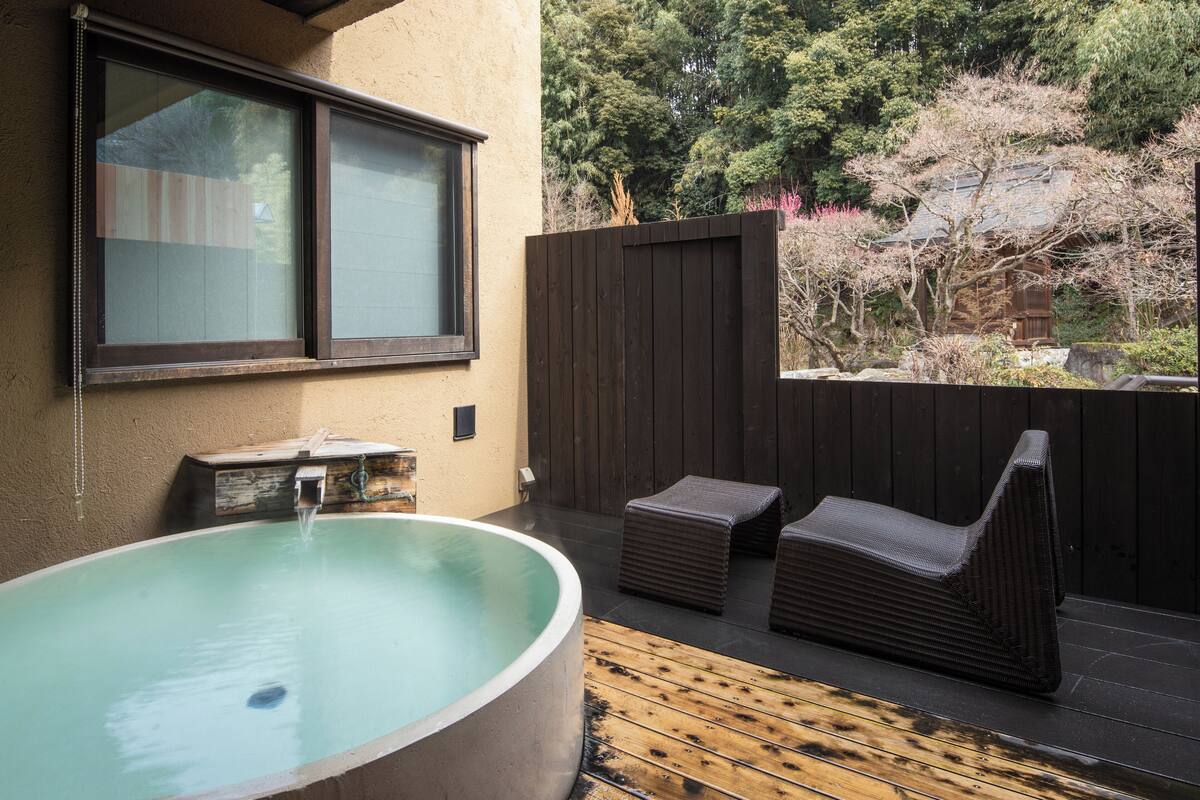 Ein Whirlpool mit Holzterrasse, Fenster und Holzzaun.