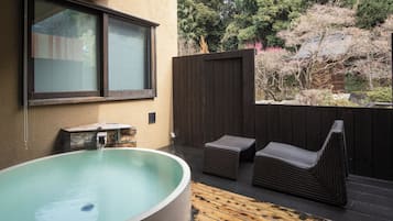 A hot tub with a wooden deck, a window, and a wooden fence.