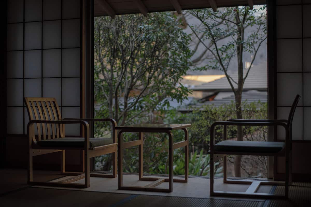 Ein traditioneller japanischer Raum mit Tatami-Bodenbelag, einem niedrigen Tisch und zwei Holzstühlen.