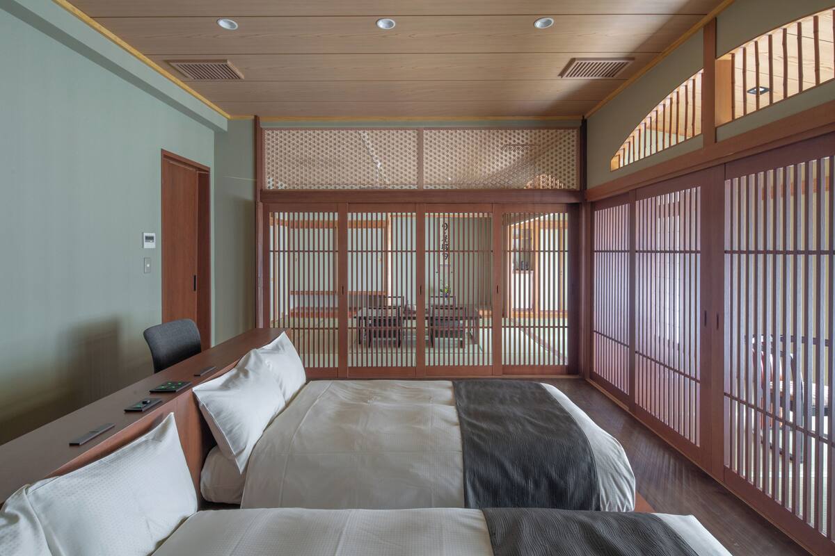 Ein Hotelzimmer mit einem großen Bett, einem Schreibtisch und Blick durch einen Shoji-Bildschirm.