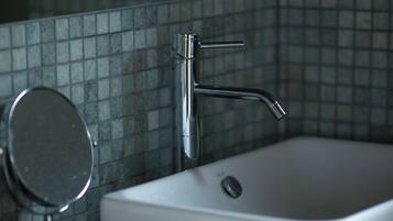 A bathroom with a white sink, a mirror, and a chrome faucet.