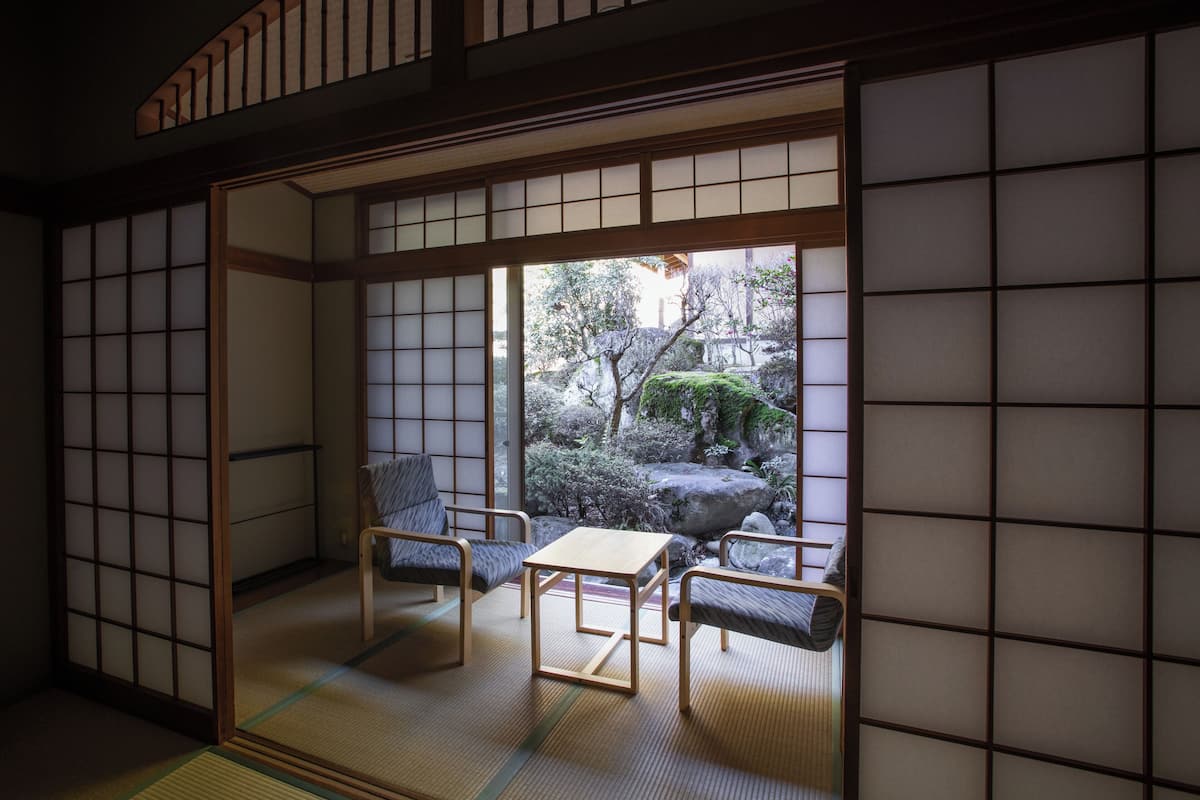 Ein traditioneller japanischer Raum mit Tatami-Boden, einem niedrigen Tisch und zwei Kissen.