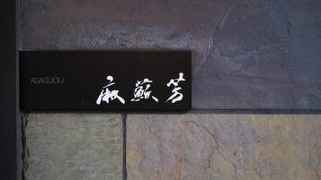 Un cartel con caracteres japoneses y el nombre 'ASASUOU' en una pared de piedra.