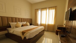 Une chambre d’hôtel moderne dotée d’un grand lit, d’un téléviseur à écran plat fixé au mur et d’un bureau en bois.