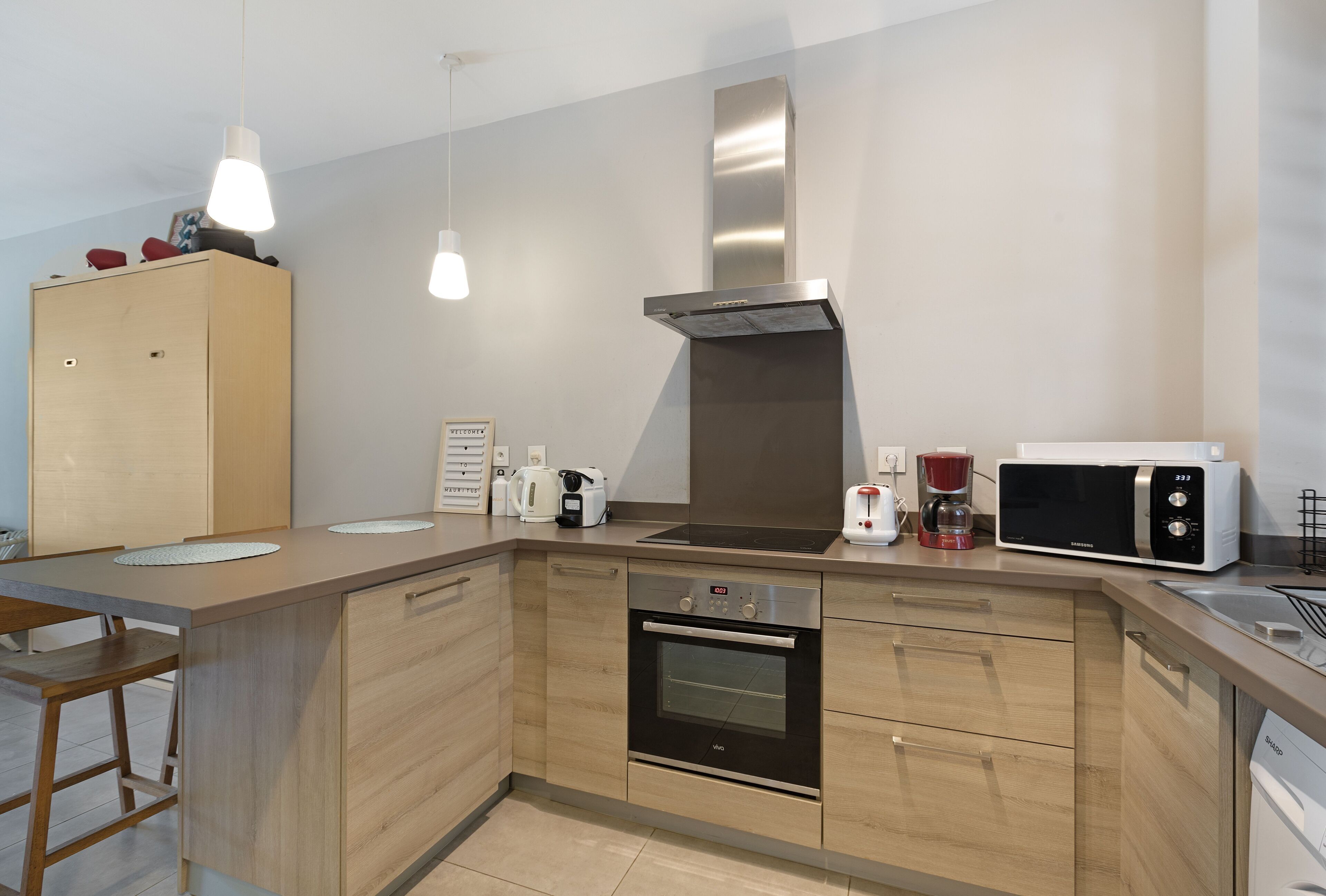 Une cuisine moderne avec des meubles en bois, un four encastré, un four à micro-ondes et une machine à café.
