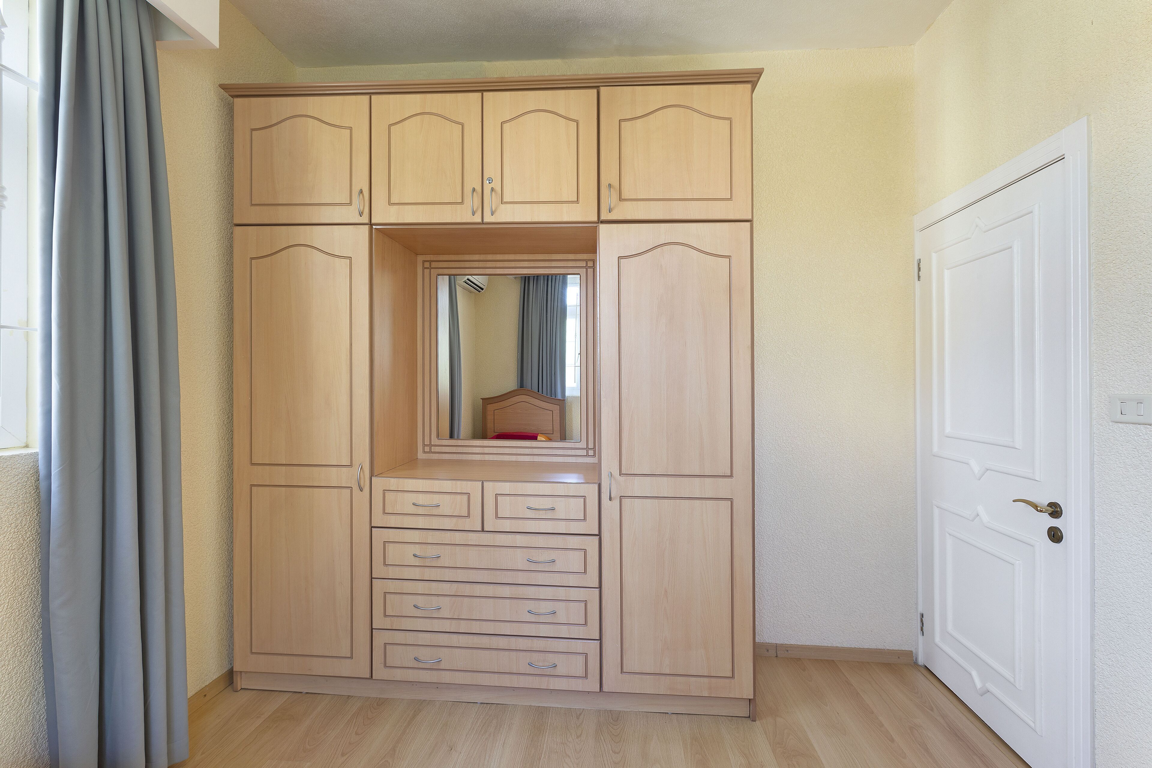 A room with a large wardrobe, a mirror, and a white door.