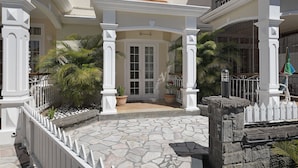 Una entrada empedrada con columnas blancas y una cerca de piquetes blancos.