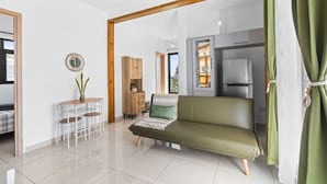 Una sala de estar moderna con un sofá, una mesa de comedor con sillas, un mueble pequeño y un espejo en la pared.