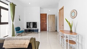 Una sala de estar moderna con televisor, asientos y comedor.