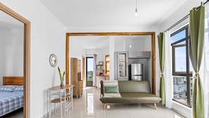 Una sala moderna con un sofá, una mesa de comedor y una cocina al fondo.