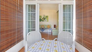 A room with a dining table, two chairs, and a view into another room with a sofa and a painting. - Apartment Hibiscus (Trou aux Biches)