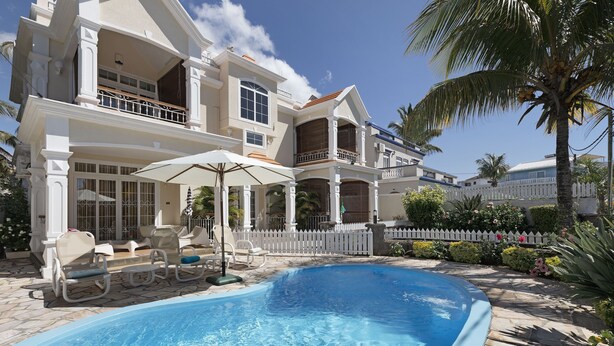 A large house with a swimming pool, outdoor furniture, and a white picket fence. - Apartment Hibiscus (Trou aux Biches)