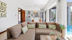 Una sala moderna con un sofá modular, una mesa de centro y vistas a una piscina.