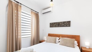 Una cama bien hecha con una colcha estampada con motivos florales, un cabecero de madera y dos mesitas de noche con lámparas.