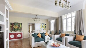Amplia sala de estar con muebles de mimbre, una mesa de comedor con un florero y un ventanal con cortinas.