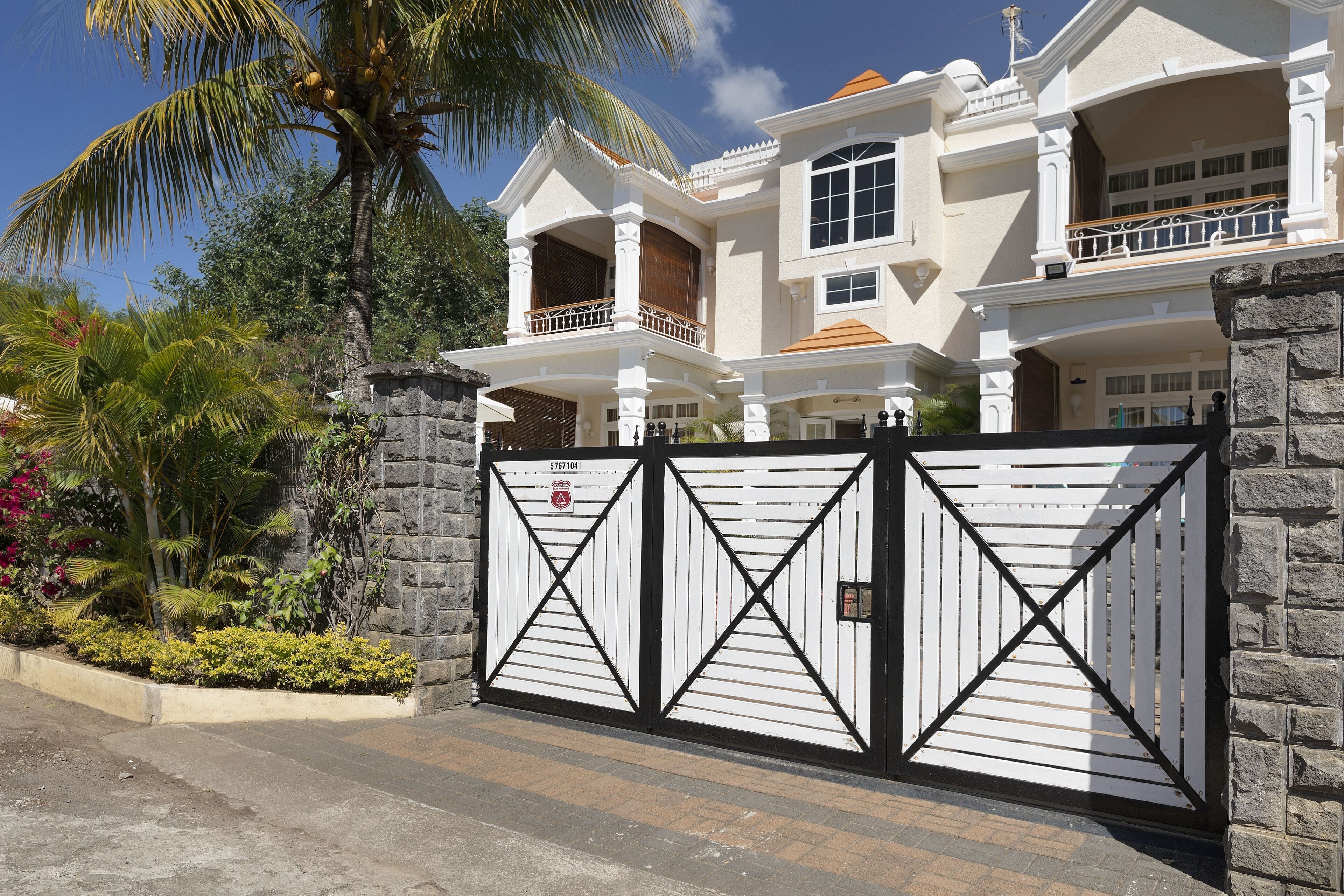 A large, two-story house with a gated entrance, stone walls, and a balcony.