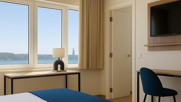 Een hotelkamer met een bed, een bureau, een stoel, een televisie en een raam met uitzicht op zee.