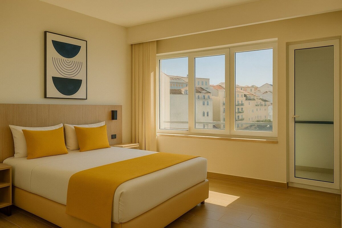 A hotel room with a bed, a nightstand, a wall-mounted artwork, a window with a city view, and a sliding door.