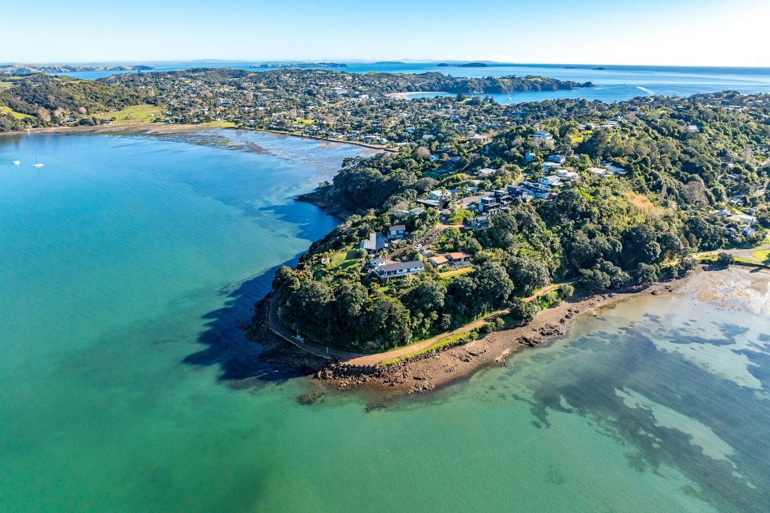 An aerial view of a coastal residential area with houses on a hillside overlooking a bay.