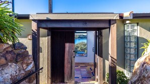 A wooden door leading to a patio with a view of a body of water and a mountain in the distance.